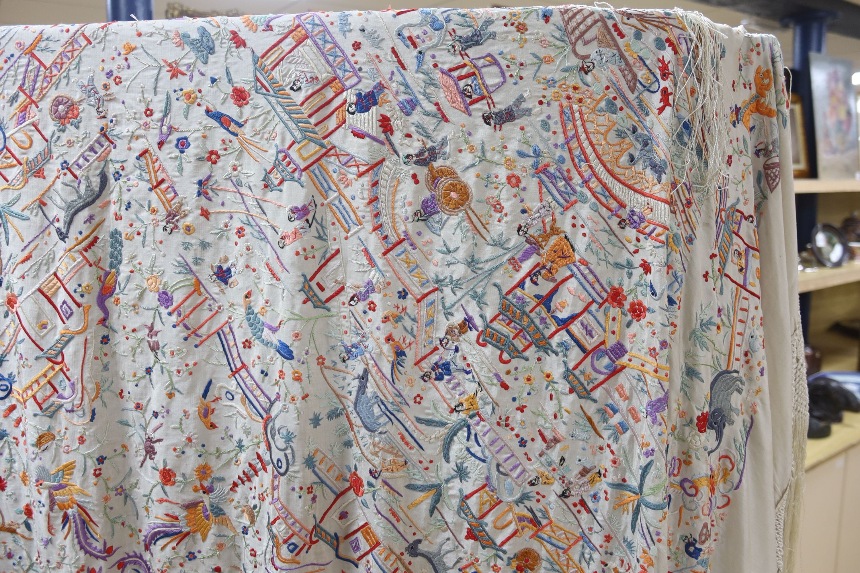 A Chinese cream silk shawl with fine multi coloured all over embroidery depicting figurative scenes and animals